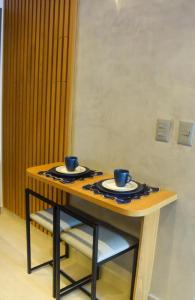 einen Tisch mit zwei blauen Bechern und Teller darauf in der Unterkunft AHA Flat in João Pessoa