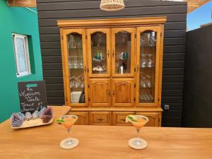 a wooden cabinet with two martini glasses on a table at La Maison Verte in Le Tampon
