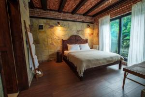 1 dormitorio con cama y pared de piedra en Elwood Hotel en Rize