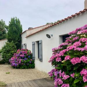 ein Haus mit rosa Blumen davor in der Unterkunft Maison vendéenne à 5 min du bord de mer in Saint-Hilaire-la-Forêt