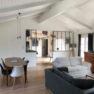 ein Wohnzimmer mit einem Sofa und einem Tisch in der Unterkunft Maison vendéenne à 5 min du bord de mer in Saint-Hilaire-la-Forêt