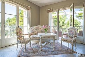 sala de estar con mesa, 2 sillas y ventanas en Villa des Fontaines luxury family home with pool, en Pernes-les-Fontaines