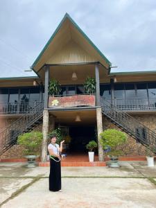 Una donna in piedi di fronte a un palazzo di Homestay Hải Long 