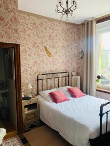 Un dormitorio con una cama con paredes rosas y una ventana en Au beau séjour 