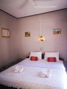 a bedroom with a white bed with two pillows at Khamphouy Guesthouse in Champasak