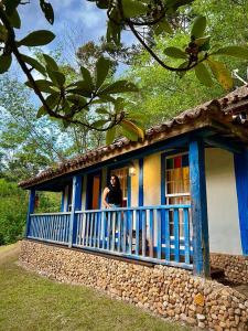 um homem de pé na varanda de uma casa azul e branca em Pousada Meu Recanto em Conceição da Ibitipoca