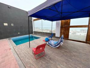 un patio con una sombrilla y sillas azules y una piscina en CASA PLAYA, en San Bartolo