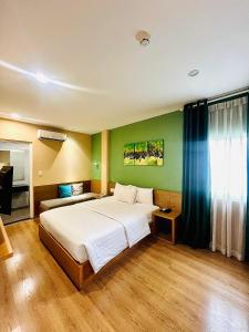 a bedroom with a large white bed and green walls at A25 Hotel - 142 Bùi Thị Xuân in Ho Chi Minh City