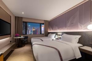 um quarto de hotel com duas camas e uma televisão em Imperial Traders Elong Hotel em Guangzhou