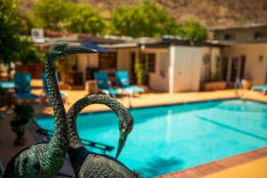 two statues of swans next to a swimming pool at Old Ranch Inn - Adults Only 21 & Up in Palm Springs