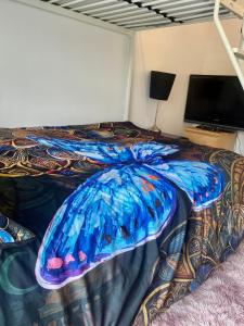 a bed with a blue comforter and a television at Double bed room in a Peaceful home in Morriston
