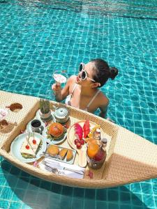 a woman sitting in a pool with a tray of food at Yuni Hotel And Apartment in Da Nang