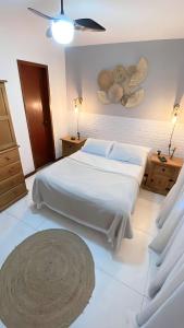 Schlafzimmer mit einem großen weißen Bett und einer Decke in der Unterkunft Casa familiar pé na areia in Cabo Frio