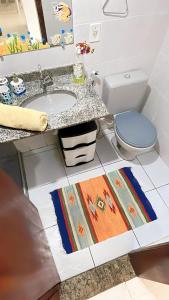 ein Badezimmer mit einem Waschbecken, einem WC und einem Teppich in der Unterkunft Casa familiar pé na areia in Cabo Frio