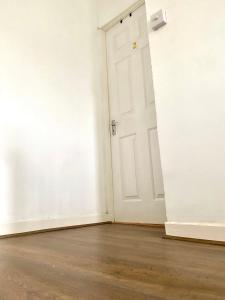 an empty room with a white door and a wooden floor at Double bed room in a Peaceful home in Morriston
