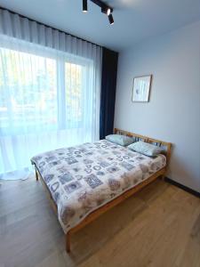um quarto com uma cama em frente a uma grande janela em AlfaHome Lodz em Lódź