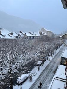 una ciudad cubierta de nieve con coches aparcados en una calle en Appart Luchon au centre des allée d'etigny, en Luchon