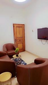a living room with two chairs and a flat screen tv at Appartement Beau Séjour 1 in Dakar