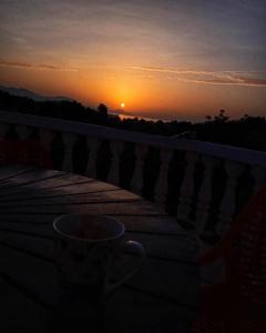 a coffee cup sitting on a balcony at sunset at Sea View Apartment Amaro in Korčula