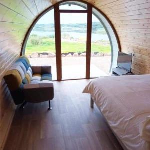 a bedroom with a bed and a couch and a window at Wheelhousepods glamping in Donegal