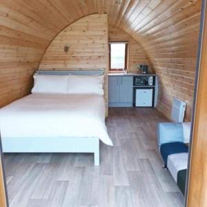 um quarto com uma cama branca num quarto de madeira em Wheelhousepods glamping em Donegal