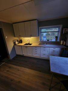 cocina con armarios blancos, fregadero y ventana en Lyngenfjord, 