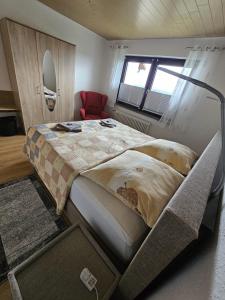 ein Schlafzimmer mit einem großen Bett und einem roten Stuhl in der Unterkunft Ferienwohnung Talblick in Weimar