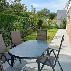 ein Glastisch und Stühle auf einer Terrasse in der Unterkunft Hartedrie vakantiewoning aan zee in De Haan