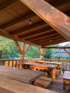 um grande pavilhão de madeira com mesas e bancos de madeira em Hotel Novoe Shale em Yablunytsya