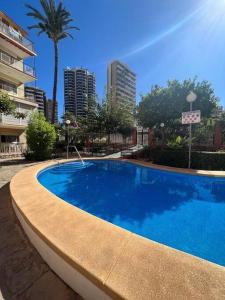 une grande piscine bleue dans une ville dans l'établissement 2 linea de playa con piscina, jardín, terraza y parking, à Benidorm