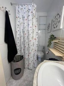 une salle de bain avec toilettes et rideau de douche dans l'établissement 2 linea de playa con piscina, jardín, terraza y parking, à Benidorm