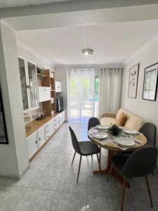 un salon avec une table et des chaises et une cuisine dans l'établissement 2 linea de playa con piscina, jardín, terraza y parking, à Benidorm 15 autres photos