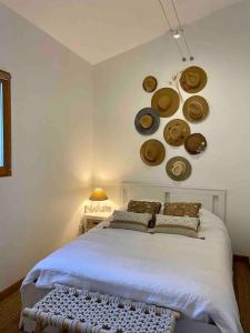 - une chambre avec un lit avec des chapeaux sur le mur dans l'établissement Gîte de charme avec piscine privative, à Bagnols-en-Forêt