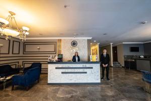 two people standing at a counter in a lobby at Hamit Hotel Kizilay in Ankara