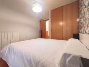 een slaapkamer met een wit bed en een houten kast bij CHECK-IN CASAS Pico de las Nieves in Benasque