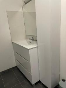 ein weißes Badezimmer mit einem Waschbecken und einem Spiegel in der Unterkunft IRIS 80 in Lorette