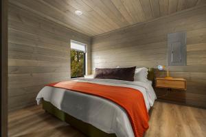 a bed in a room with wooden walls and a window at Hidden Acres Vestur Cabin in Petoskey