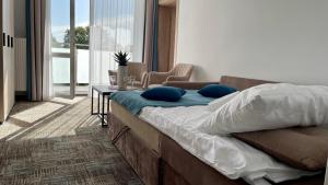 a bedroom with a bed with blue pillows and a table at Apartament Welle Lazurowy PREMIUM Grzybowo in Grzybowo