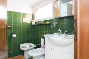 uma casa de banho com azulejos verdes, um lavatório e um WC. em Nido di Stella em Zanica