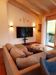 a living room with a large couch and a flat screen tv at Herzbluad Chalet in Wallgau