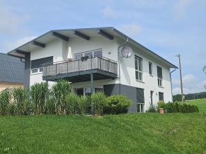 a white house with a balcony and a lawn at Haus am Brunnen Wohnung 1 in Klosterkumbd
