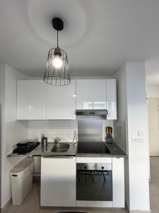 a kitchen with white cabinets and a pendant light at Appartement avec Terrasse et box in Marseille