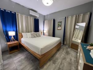 1 dormitorio con cama, lámpara y cortinas azules en Casa Lambí, en Cabrera