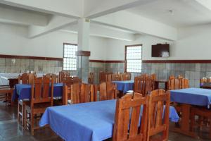 comedor con mesas azules y sillas de madera en Hotel Estalagem Sertaneja, en Brumado
