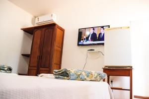 1 dormitorio con 1 cama y TV en la pared en Hotel Estalagem Sertaneja, en Brumado