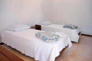2 camas en una habitación con paredes blancas en Hotel Estalagem Sertaneja, en Brumado