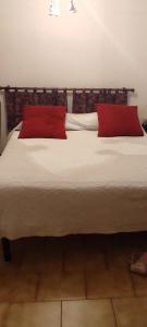 1 cama grande con 2 almohadas rojas. en Appartamento IL QUADRIFOGLIO, en Saint-Oyen