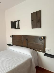 1 cama con cabecero de madera en una habitación en Casa rural las pelliquerinas, en Almoharín