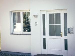 uma casa branca com uma porta e uma janela em Ferienwohnung mit Terrasse am Nationalpark Jasmund em Neddesitz