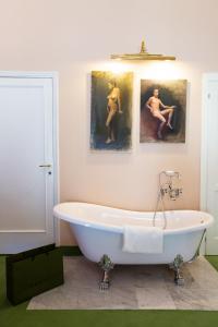 a bath tub in a bathroom with two paintings on the wall at Stella d'Italia in Florence +67 photos